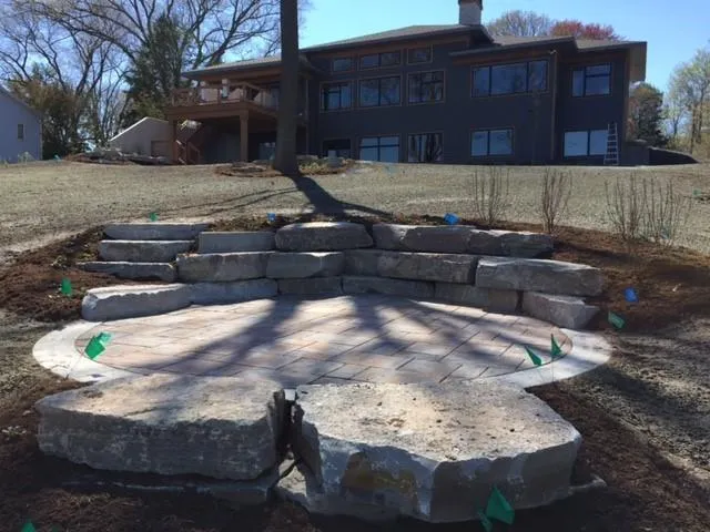Backyard paver patio with seating wall and fire feature.