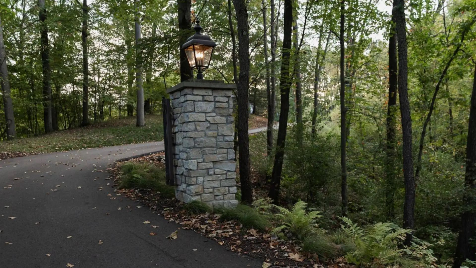 landscape lighting design Grand Rapids with illuminated entry column, woodland drive, and soft outdoor lighting for curb appeal and safety